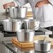 A chef using a Choice tapered aluminum sauce pan to prepare food.