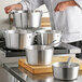 A chef holding a Choice tapered aluminum sauce pan.