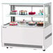 A Turbo Air white refrigerated bakery display case with cakes on it.