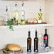 A shelf with Tablecraft dark green glass oil and vinegar bottles filled with yellow liquid.