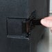 A finger opening a black box with a black handle.
