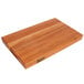 A John Boos cherry wood cutting board with hand grips on a table.