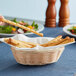 A person holding bread sticks in a Tablecraft oval basket.