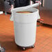 A man holding a large white round mobile ingredient storage bin with a white snap-on lid.