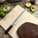 A Shun Classic Forged Slicing Knife on a cutting board next to a piece of meat.