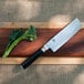 a knife and a piece of broccoli on a wooden board