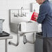 A man washing his hands in a Regency utility hand sink on a counter.