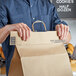 A person using a 16" handle cuff tamper evident seal on a brown paper bag.