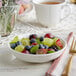 A bowl of fruit in an Acopa Condesa scalloped porcelain fruit bowl on a table.