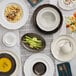 An Acopa matte gray porcelain mug on a table with white plates and food.