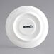 An Acopa white porcelain scalloped saucer with black text.