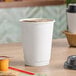 A white Choice double wall paper hot cup filled with brown liquid on a table.