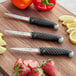 A Schraf paring knife set with three knives on a cutting board.