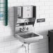 A stainless steel Regency wall mounted hand sink with top mounted soap and paper towel dispensers.