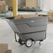 A gray Lavex 1 cubic yard standard-duty tilt truck or trash cart with a 1250 lb. capacity, shown holding cardboard boxes in a warehouse setting.