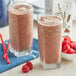 A close up of two glasses of chocolate milked oats with raspberries on top.