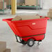 A red heavy-duty tilt truck or trash cart with a 0.5 cubic yard capacity, designed for transporting materials or waste in industrial settings.