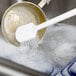 A person using a Carlisle Sparta pot scrub brush to clean a sink in a professional kitchen.