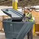 A woman placing a garbage bag into a Lavex gray tilt truck lid.