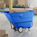 A blue heavy-duty tilt truck or trash cart with a 1 cubic yard capacity, designed for transporting materials in industrial or commercial settings.