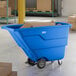 A blue Lavex 1 cubic yard light-duty tilt truck or trash cart with an 850 lb. capacity, shown in a warehouse setting with cardboard boxes inside.
