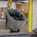 A woman pushing a Lavex grey tilt trash cart.