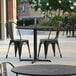 A Lancaster Table & Seating Excalibur table and chairs on an outdoor patio.