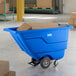 A blue Lavex tilt truck or trash cart with a 0.5 cubic yard capacity, holding cardboard boxes in a warehouse setting.