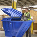 A woman in a safety vest holding a black bag is putting it in a blue Lavex tilt truck.