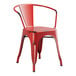 A red Lancaster Table & Seating outdoor arm chair with metal arms and back.