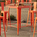 An orange bar table with chairs on an outdoor patio.