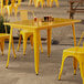 A Lancaster Table & Seating citrine yellow outdoor table on a stone patio.