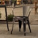 A Lancaster Table & Seating black metal outdoor arm chair on a patio.