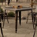 A Lancaster Table & Seating distressed copper table with glasses of beer on it on an outdoor patio.