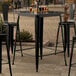 A Lancaster Table & Seating black metal table with a glass of beer on it.