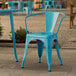 A turquoise Lancaster Table & Seating outdoor arm chair on a stone patio.