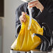 A woman using a French's yellow mustard pouch with a fitment to pour mustard into a sink.