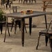 A Lancaster Table & Seating Distressed Copper Outdoor Table with chairs on a patio.