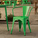 A green Lancaster Table & Seating outdoor arm chair on a stone patio.