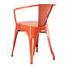 A Lancaster Table & Seating orange metal outdoor arm chair with a backrest.