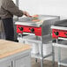 A man using an Avantco countertop gas griddle to cook food in a professional kitchen.