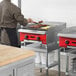 An Avantco Chef Series gas countertop charbroiler being used to cook food.