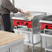 A man using an Avantco Chef Series countertop gas griddle to cook food in a professional kitchen.