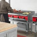 A man cooking food on an Avantco gas countertop charbroiler.