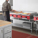 A man in a black apron cooking on an Avantco Chef Series countertop gas griddle.