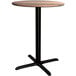 A Lancaster Table & Seating Excalibur round wooden table with a black base.