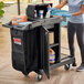 A woman cleaning a black Suncast housekeeping cart.