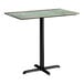 A rectangular bar height table with a textured faux metal finish top and a black cross base plate.