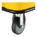 A close-up of a caster wheel attached to a yellow Lavex 8 cubic foot cube truck.