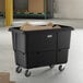 A large black cube truck with wheels, used for transporting materials, containing cardboard boxes.